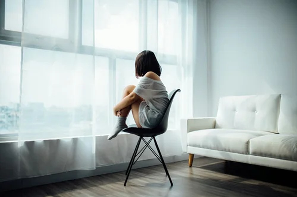A woman sitting quietly by a bright window