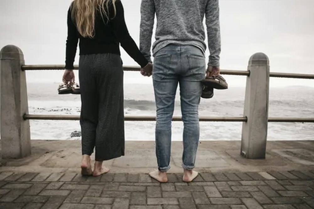 A couple holding hands, looking out at the water